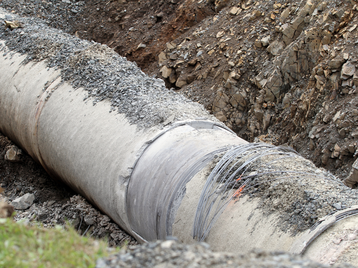 large water main pipe in ground surrounded by dirt