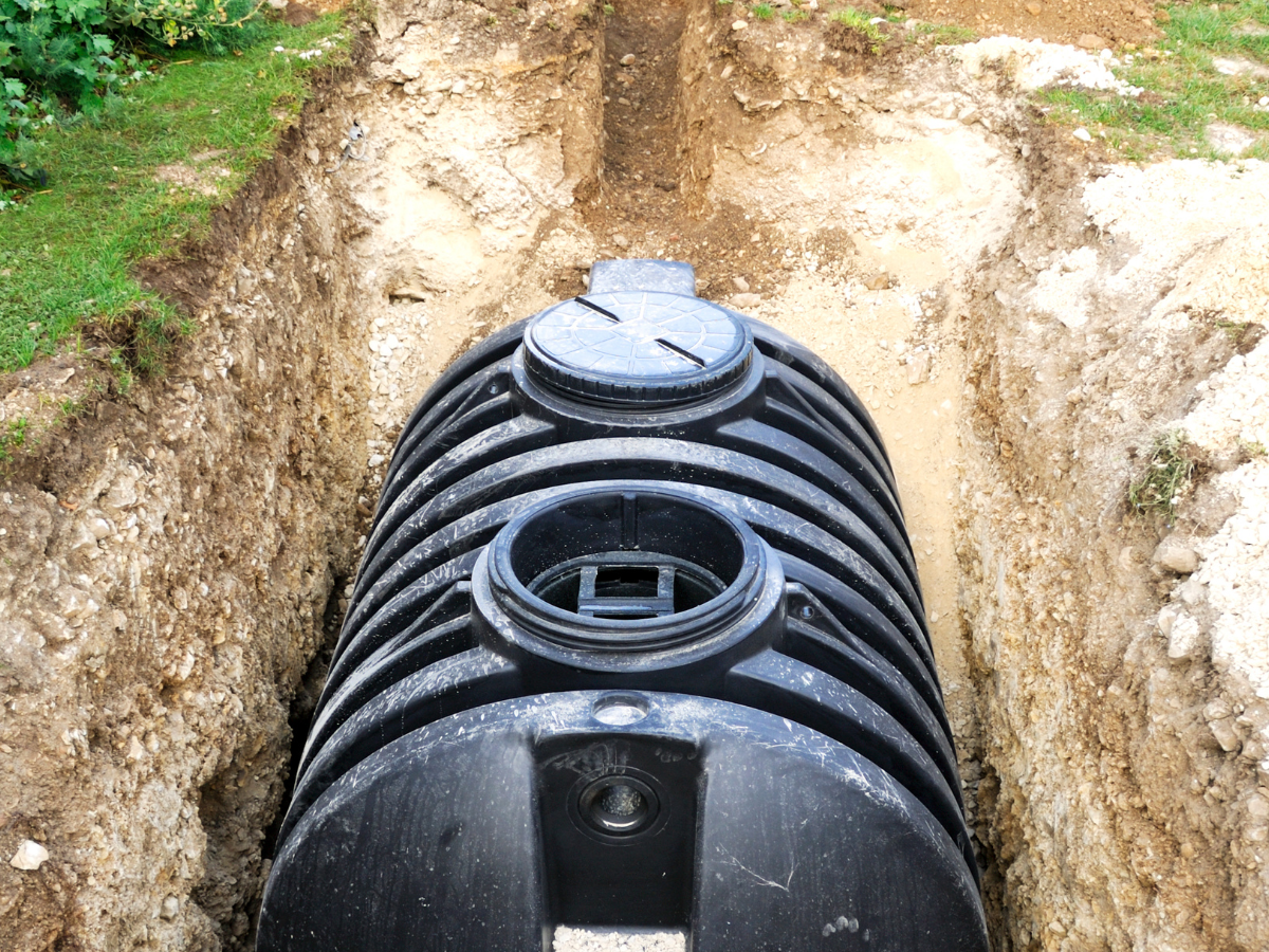 black septic tank in ground surrounded by dirt